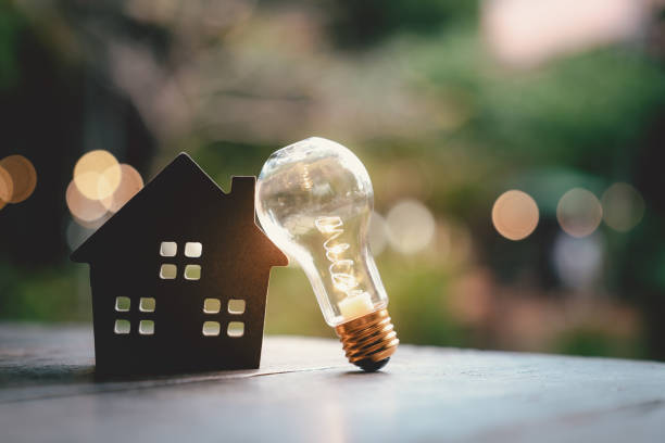 ampoule avec maison en bois sur la table, un symbole pour la construction, idée d’ampoule créative, énergie de puissance ou l’écologie concept d’idée d’entreprise, prêt, hypothèque, propriété ou maison. - electricité photos et images de collection